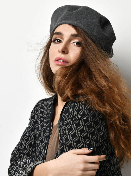 Fiatal szexi barna nő szürke beret kalapját, és nézte a sarokban kabát - Fotó, kép