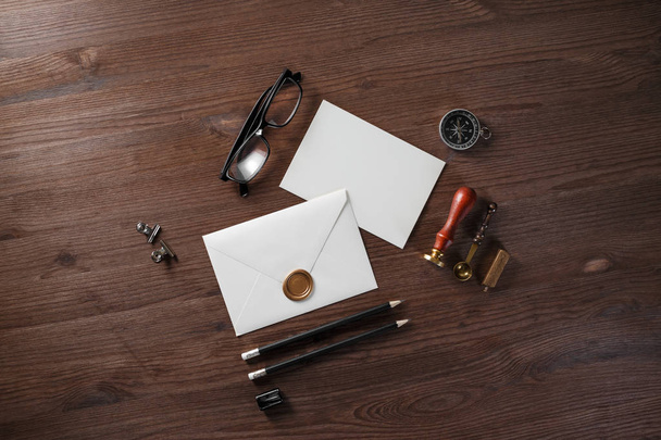 Blank paper envelope with wax seal and stationery on wood table background. Flat lay. - Foto, Bild