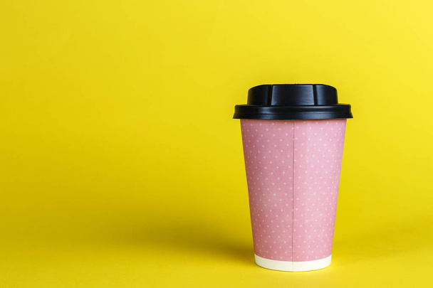 pink cardboard cup for coffee with a lid on a yellow backgroun - Fotó, kép