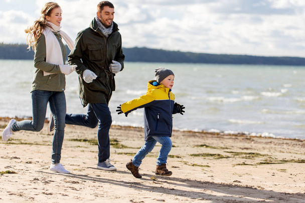 happy family running along autumn beach - Foto, Imagen