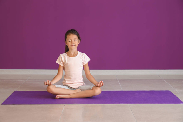 Little girl practicing yoga indoors - Fotó, kép