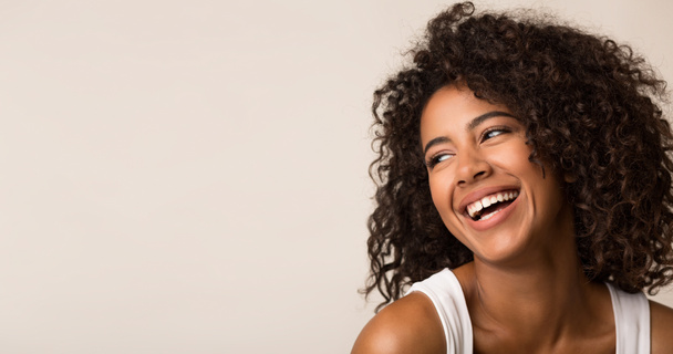 lachende afrikanisch-amerikanische Frau, die auf hellem Hintergrund wegschaut - Foto, Bild