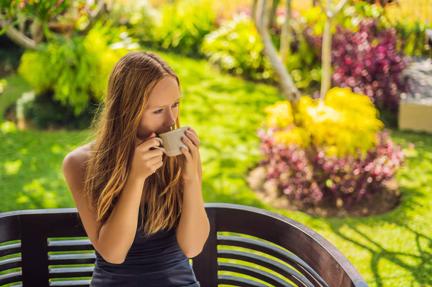 Woman drinking coffee on terrace at sunny day - Фото, изображение