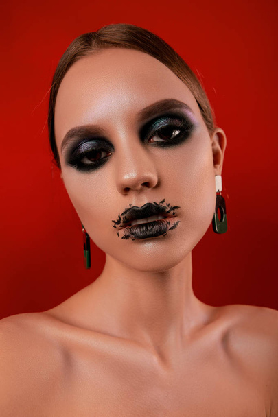 Retratos de belleza de una hermosa chica con maquillaje en estilo Halloween sobre un fondo rojo
 - Foto, Imagen