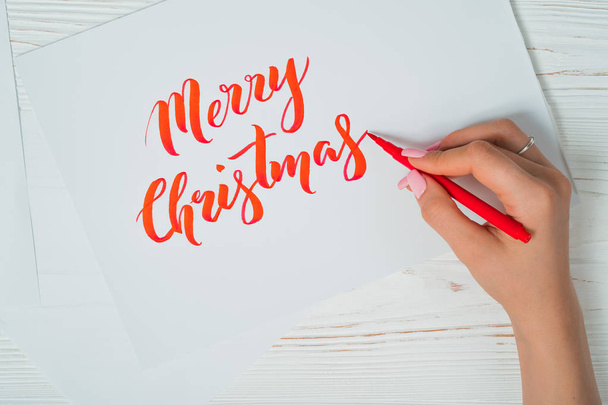 Merry Christmas congratulations. Calligrapher writes with red ink on white card. Calligraphy. Ornament font. The art of lettering. Graphic design, handwriting, creation concept. - Photo, Image