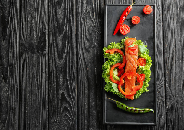 Тарілка зі смачним лососем і свіжим салатом на дерев'яному столі
 - Фото, зображення
