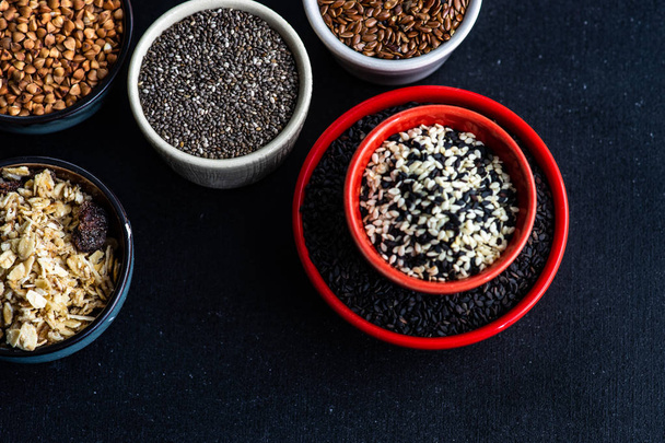 Ποικιλία των superfoods σε κεραμικά κύπελλα σε σκούρο φόντο ξύλινη - Φωτογραφία, εικόνα