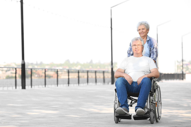 Homme âgé en fauteuil roulant et sa femme à l'extérieur
 - Photo, image