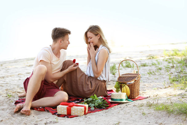 Молодой человек делает предложение своей девушке на романтическом свидании возле Ривер
 - Фото, изображение