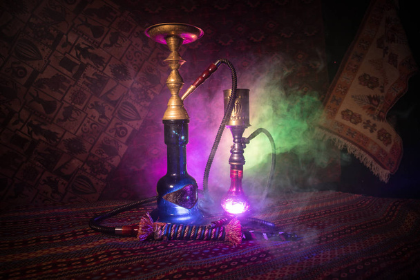 Shisha glühende Kohlen auf Shisha-Schüssel machen Dampfwolken im arabischen Inneren. orientalische Ornamente auf dem Teppich. stilvolle orientalische Shisha im Dunkeln mit Hintergrundbeleuchtung. für Shisha-Werbung. Selektiver Fokus - Foto, Bild