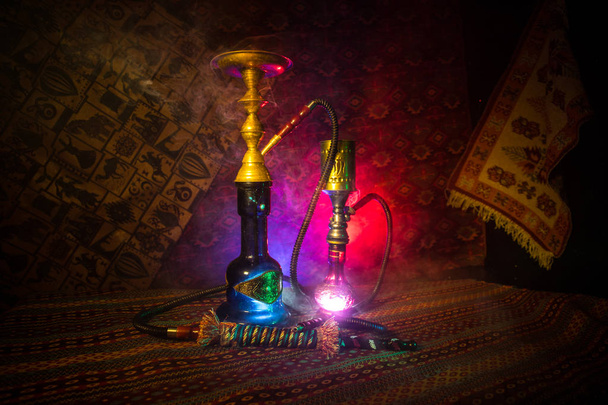 Hookah hot coals on shisha bowl making clouds of steam at Arabian interior. Oriental ornament on the carpet. Stylish oriental shisha in dark with backlight. For Shisha advertisement. Selective focus - Photo, Image