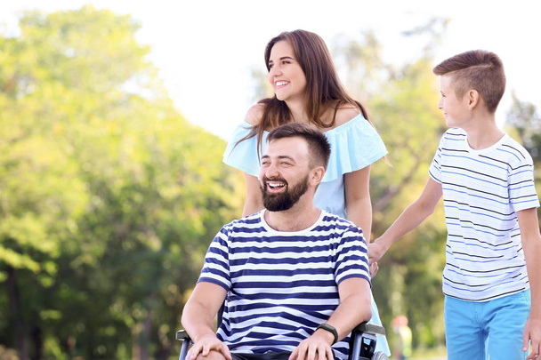 Young man in wheelchair with his family walking outdoors - Foto, Imagem