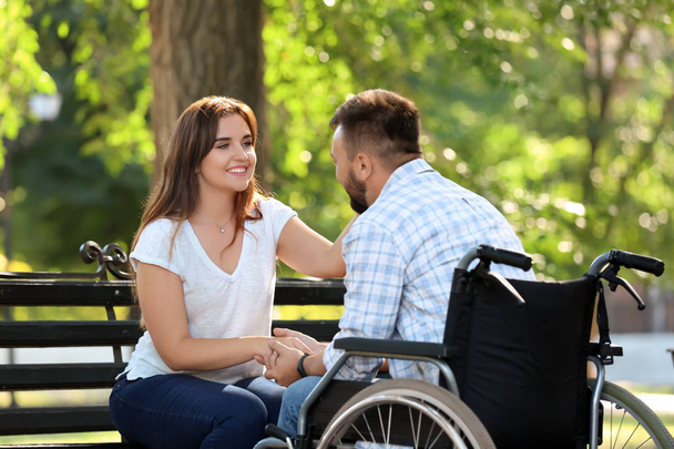 Молодой человек в инвалидной коляске с женой на улице
 - Фото, изображение