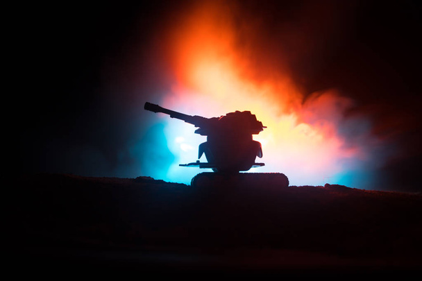 Sota-ajatus. Panssaroitu säiliö siluetti alla sumuinen palo taivas yöllä. Hyökkäyskohtaus. Lelujen koristeluun. Valikoiva painopiste
 - Valokuva, kuva