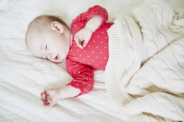 Baby girl sleeping under knitted blanket. Little child in pink clothes having a day nap. Infant kid in nursery - Foto, Imagem