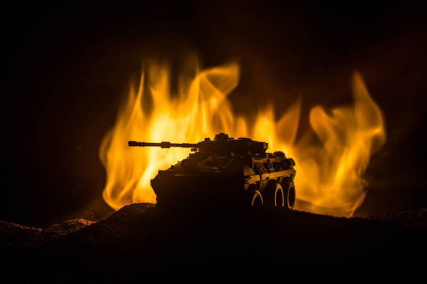 Kriegskonzept. Panzer Silhouette unter nebligem Feuerhimmel in der Nacht. Angriffsszene. Spielzeugdekoration. Selektiver Fokus - Foto, Bild