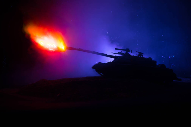 Sota-ajatus. Panssaroitu säiliö siluetti alla sumuinen palo taivas yöllä. Hyökkäyskohtaus. Lelujen koristeluun. Valikoiva painopiste
 - Valokuva, kuva