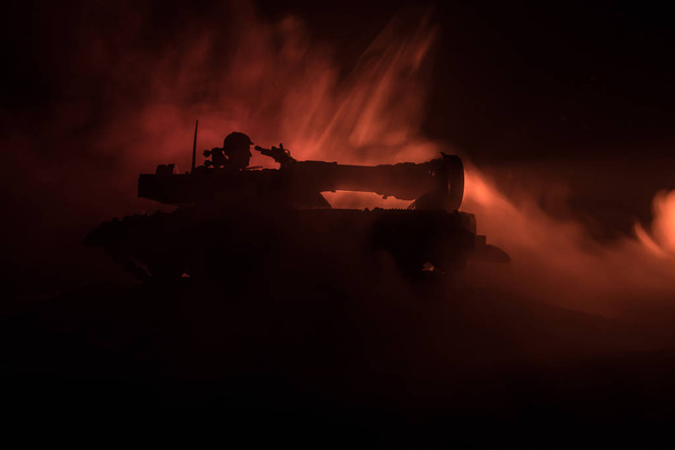 Savaş kavramı. Zırhlı Tank siluet aşağıda sisli yangın gökyüzü gece. Saldırı sahne. Oyuncak dekorasyon. Seçici odak - Fotoğraf, Görsel