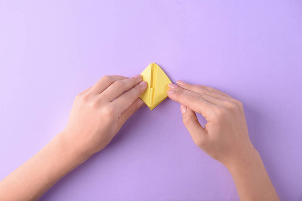 Woman making origami boat on color background - Foto, immagini