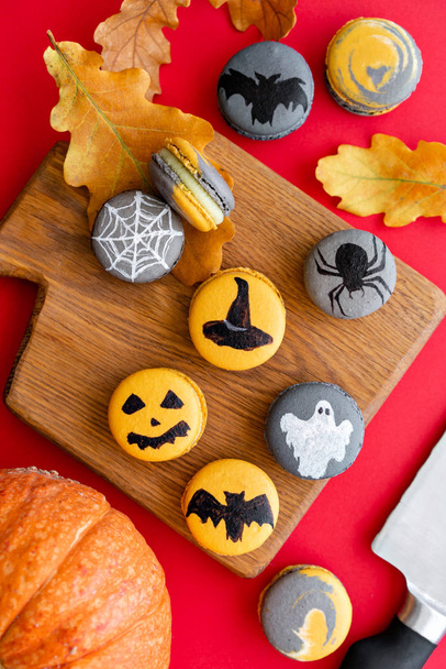Halloween scary cookies with pumpkin on wooden cut board. pattern Bat , patina, ghosts and spiders. Red color background, top view - Foto, Bild