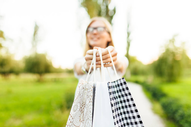 дівчина в окулярах, одягнена в білу футболку, повертається після покупки, зберігає покупку, перебуваючи в парку
 - Фото, зображення