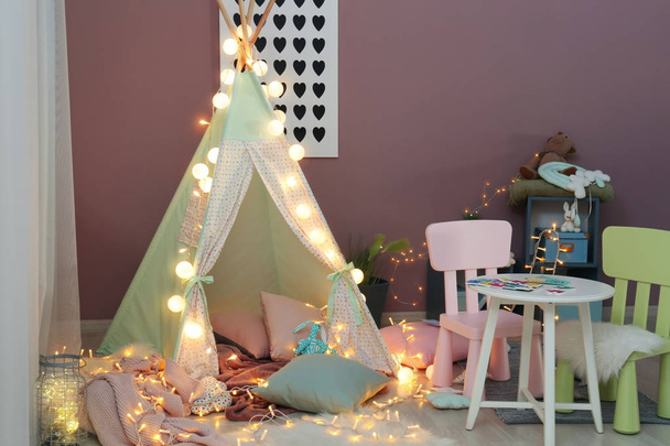Accogliente tenda da gioco per bambini con ghirlanda luminosa all'interno della stanza
 - Foto, immagini