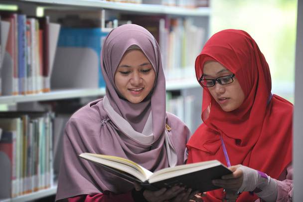 Due giovani studenti di muslimah discutono in biblioteca
. - Foto, immagini