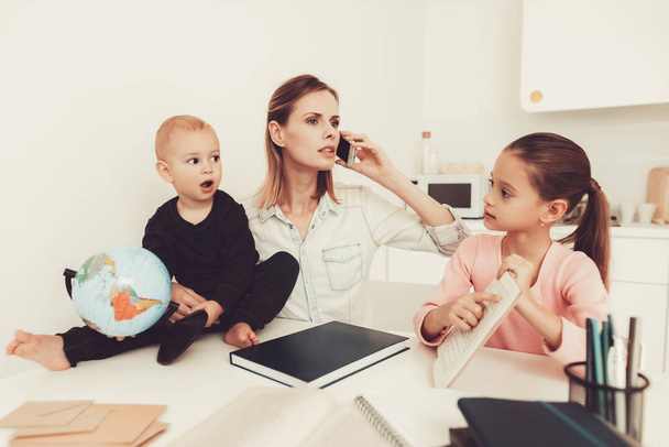 Mom Helps Daughter To Do Homework In The Kitchen. Family Relationship Concept. Educational Childhood. Studying At Home. Knowledge Receiving. Hold A Baby. Play With Globe. Working Together. - 写真・画像