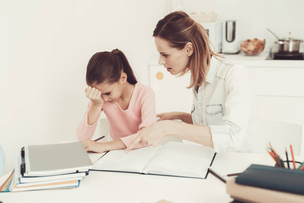 Mom Helps Daughter To Do Homework In The Kitchen. Family Relationship Concept. Educational Childhood. Studying At Home. Knowledge Receiving. Information Writing. Parents Duty. Working Together. - Φωτογραφία, εικόνα