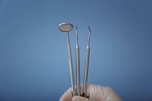 Dentista in possesso di strumenti in acciaio su sfondo colore
 - Foto, immagini