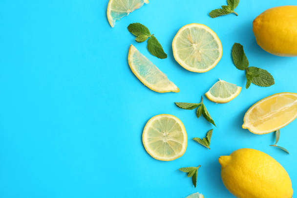 frische Zitronen und grüne Blätter auf farbigem Hintergrund, flache Lage - Foto, Bild