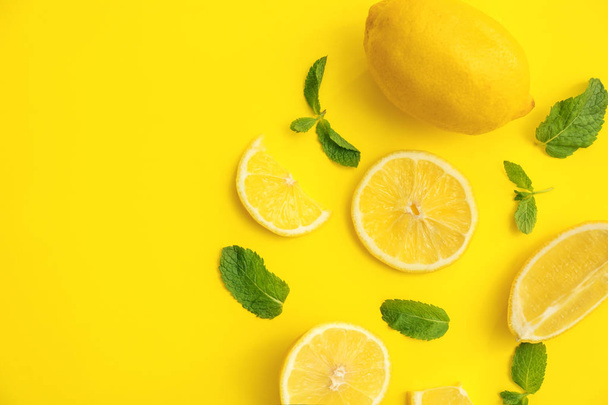 Fresh lemons and green leaves on color background, flat lay - Foto, Bild