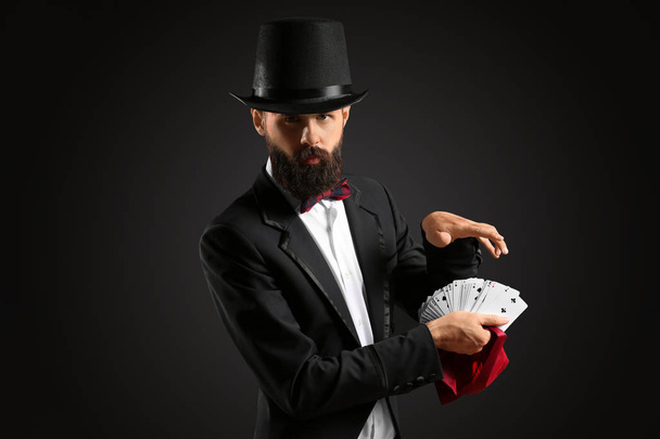 Magician with cards on dark background - Photo, Image