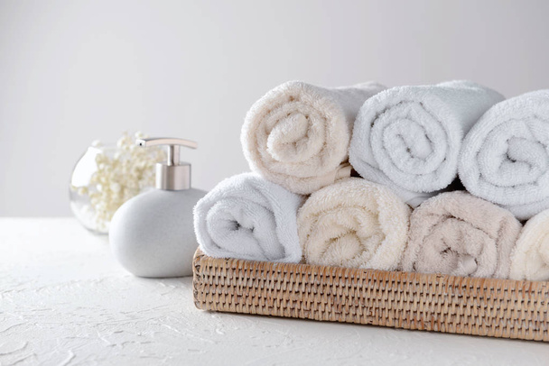 Wicker tray with rolled clean towels on table - Photo, Image