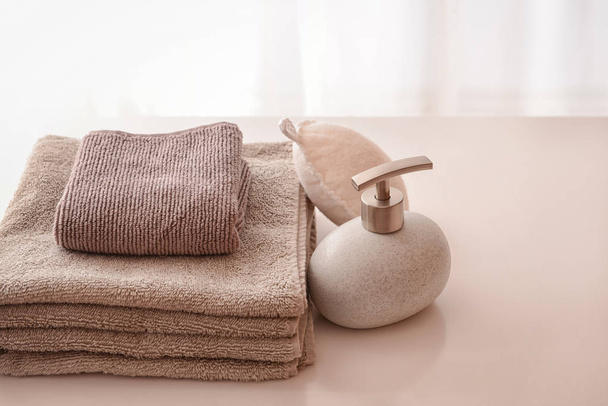 Чистые полотенца и бутылка с мылом на столе
 - Фото, изображение