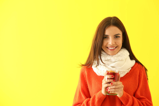 Femme avec tasse en verre de délicieux vin chaud sur fond de couleur
 - Photo, image