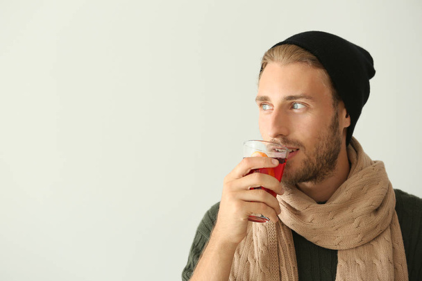 Man drinking delicious mulled wine on light background - Photo, Image