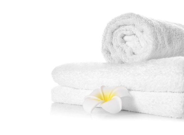 Empilement de serviettes propres et douces avec fleur sur fond blanc
 - Photo, image