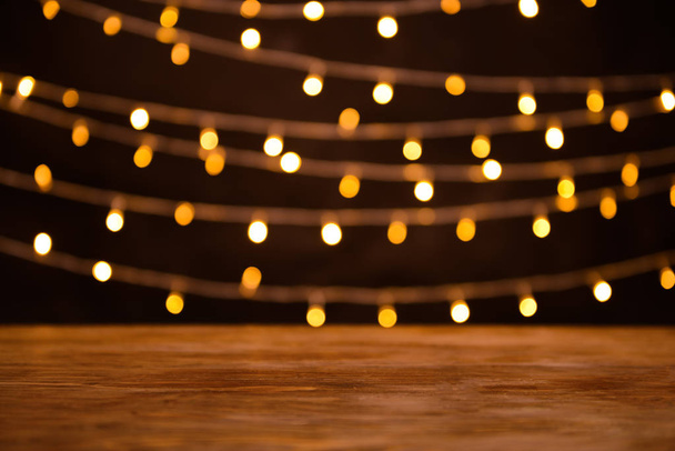 Closeup view of wooden table with glowing lights - Фото, зображення