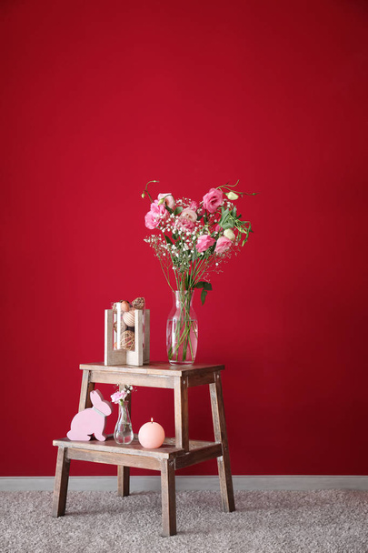 Interior decorations and vase with beautiful pink flowers on wooden stand near color wall - Photo, Image