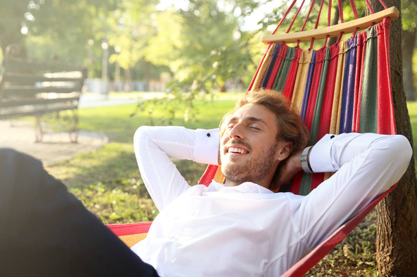 Guapo joven hombre de negocios descansando en hamaca al aire libre
 - Foto, imagen