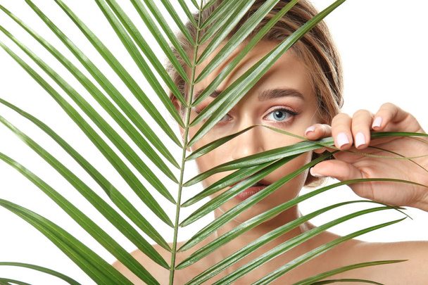 Красивая молодая женщина с обнаженным макияжем и пальмовым листом на белом фоне
 - Фото, изображение