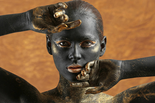 Belle femme avec peinture noire et dorée sur son corps sur fond de couleur
 - Photo, image