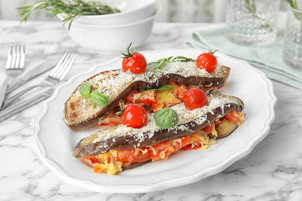 Baked eggplant with tomatoes, cheese and basil on marble table - Photo, image