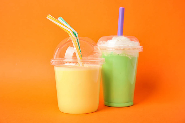 Plastic cups of tasty milk shakes on color background - Photo, image