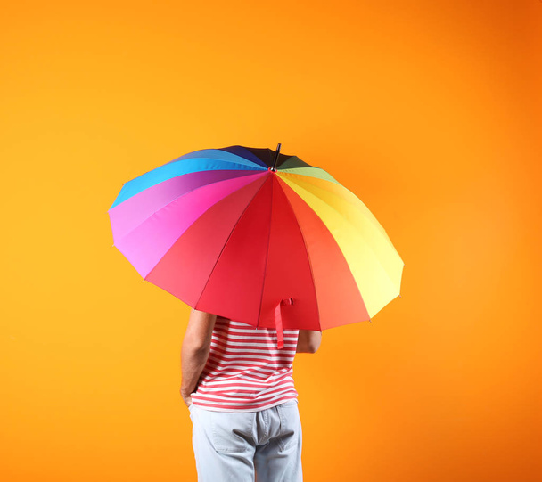 Man with rainbow umbrella on color background - Photo, image