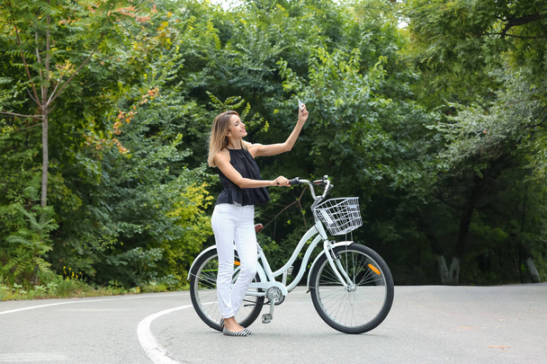 Beautiful woman in casual outfit with bicycle outdoors - Φωτογραφία, εικόνα