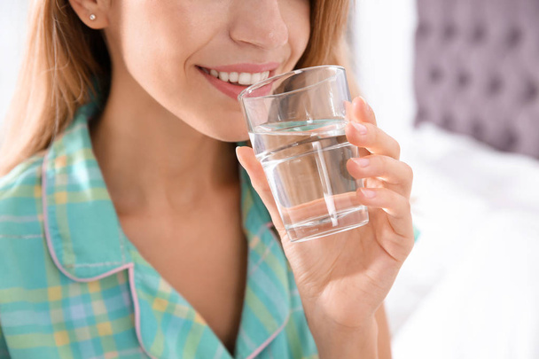 Young woman drinking water from glass indoors, closeup - Foto, Bild