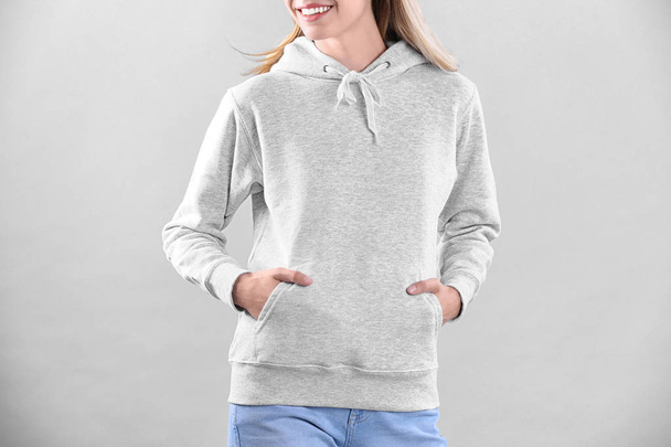 Woman in hoodie sweater on light background. Space for design - Φωτογραφία, εικόνα