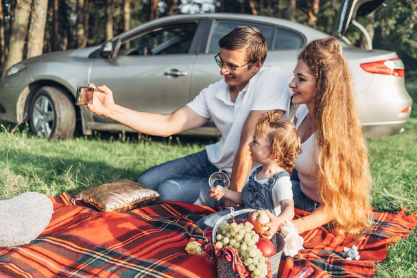 Fiatal pár szórakozik a parkban, a városon kívül, családi hétvége piknik koncepció, három ember élvezi nyári kis lányuk - Fotó, kép